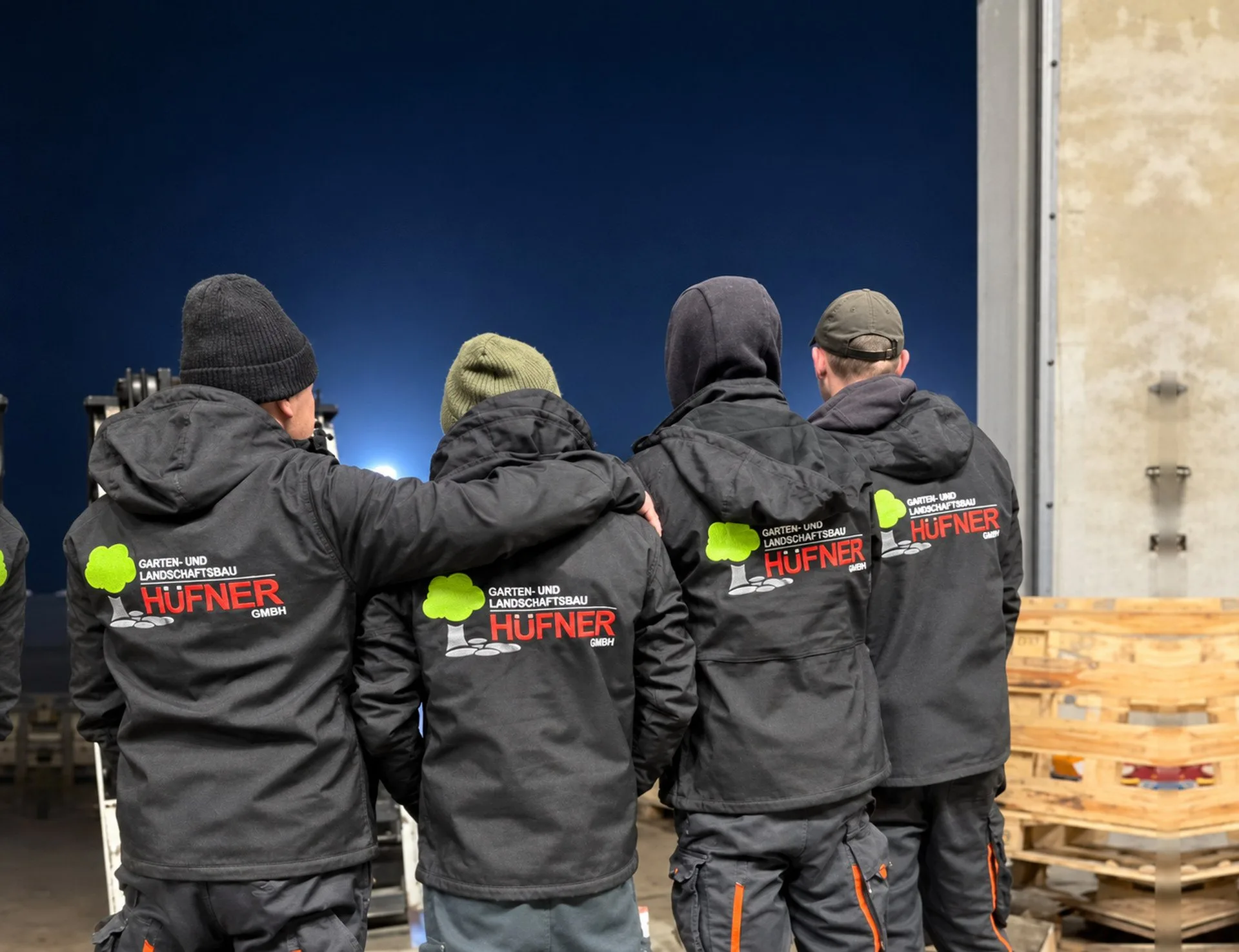 Das Hüfner-Team in Arbeitsjacken mit Firmenlogo
